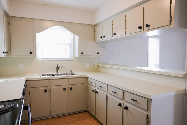 kitchen with cream cabinets, sink, light hardwood / wood-style floors, and electric stove