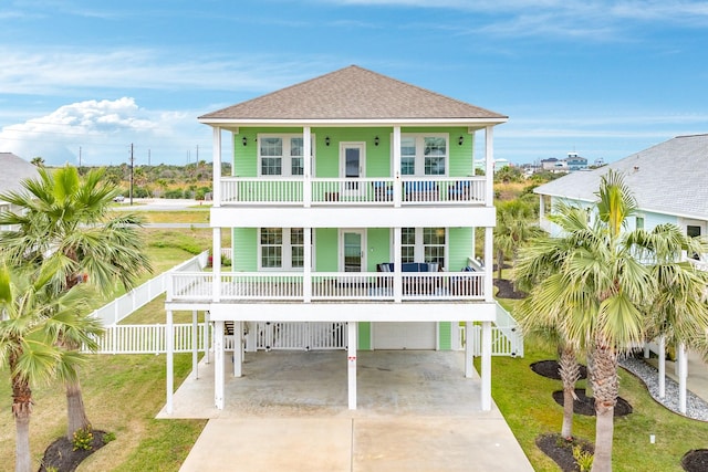 coastal inspired home featuring a garage, a carport, a balcony, and a front yard