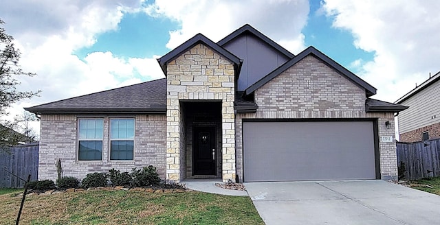 view of front of home with a front lawn, fence, concrete driveway, an attached garage, and a shingled roof