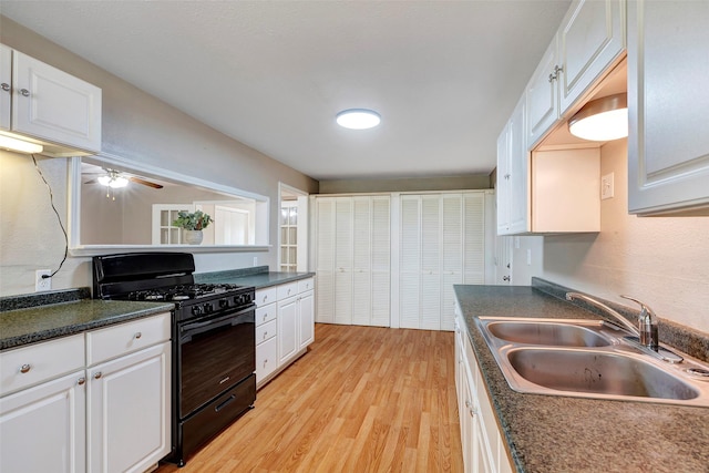 kitchen with sink, ceiling fan, black gas stove, white cabinetry, and light hardwood / wood-style floors