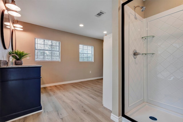 bathroom with wood-type flooring, vanity, and a tile shower