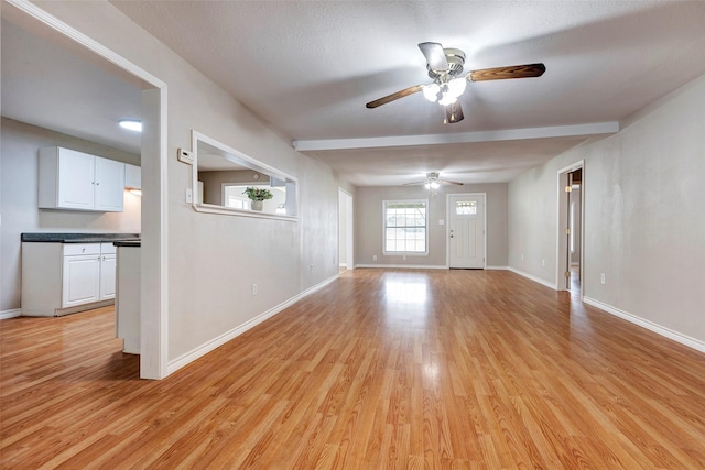 empty room featuring a textured ceiling, ceiling fan, and light wood-type flooring