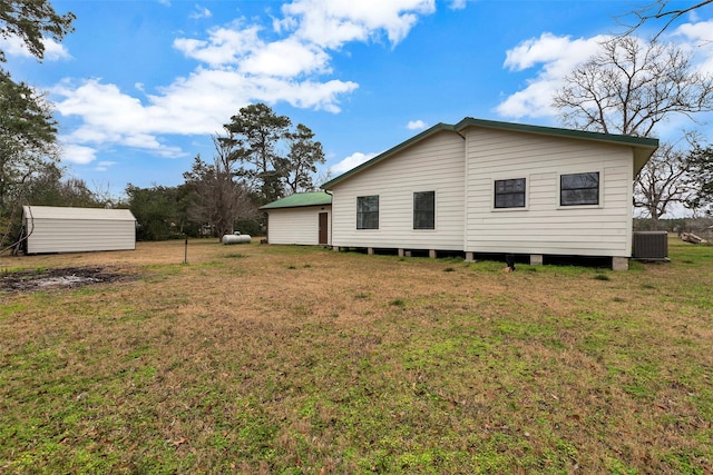 back of property with central AC unit and a lawn