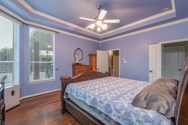 bedroom featuring a raised ceiling, ornamental molding, dark wood-type flooring, and ceiling fan