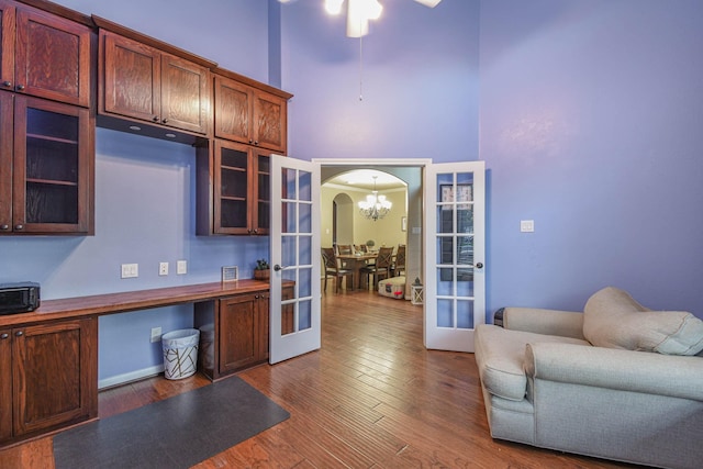 home office featuring a high ceiling, dark wood-type flooring, a notable chandelier, and french doors