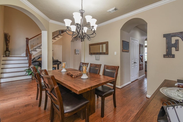 dining space with dark hardwood / wood-style flooring, crown molding, and an inviting chandelier