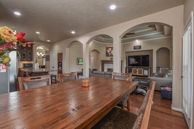 dining space with a raised ceiling, ornamental molding, a textured ceiling, and dark hardwood / wood-style flooring