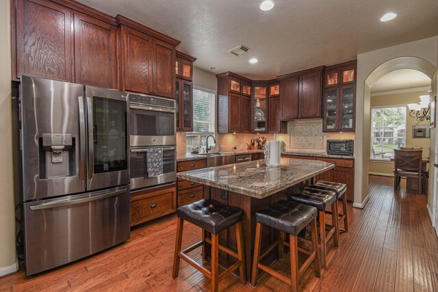 kitchen featuring sink, appliances with stainless steel finishes, dark stone countertops, tasteful backsplash, and a kitchen island