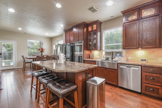 kitchen with a kitchen island, sink, a breakfast bar area, stainless steel appliances, and light hardwood / wood-style flooring