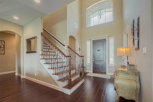 entryway featuring dark wood-type flooring, a towering ceiling, and a healthy amount of sunlight