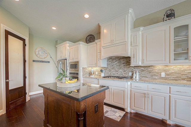 kitchen featuring dark wood-type flooring, appliances with stainless steel finishes, a kitchen island, and white cabinets