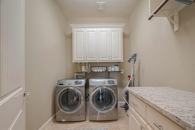 laundry room with cabinets, light tile patterned floors, a textured ceiling, and washer and clothes dryer