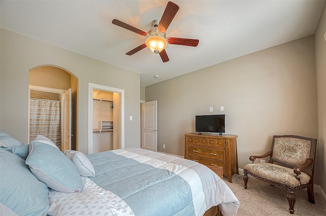 carpeted bedroom with a walk in closet and ceiling fan