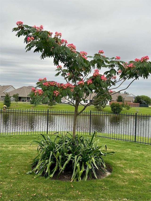 view of yard featuring fence, a water view, and a residential view