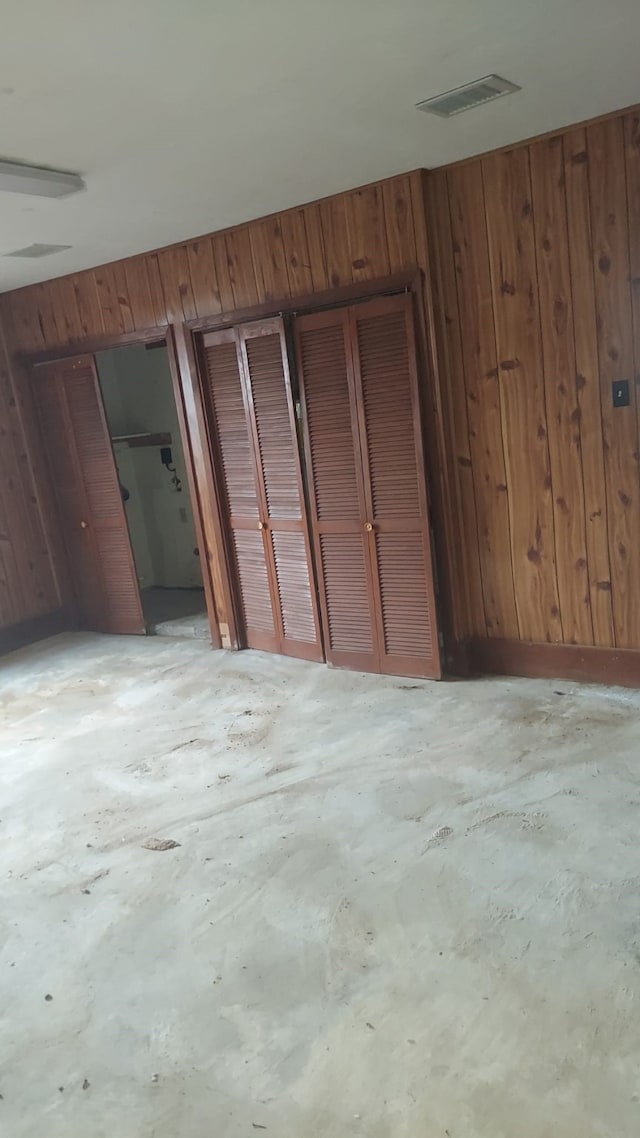 unfurnished bedroom featuring wooden walls and multiple closets