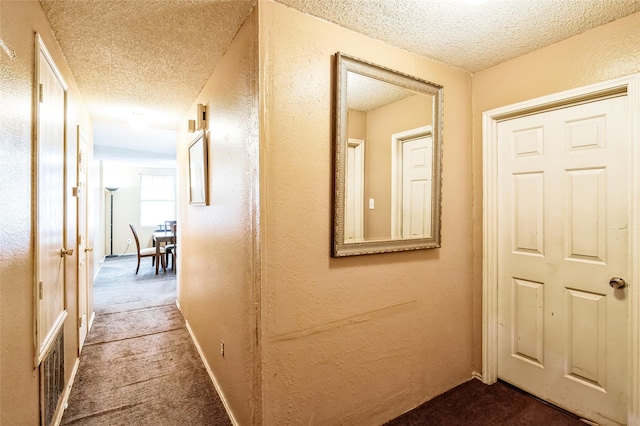 hallway featuring carpet and a textured ceiling