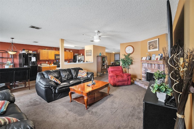 carpeted living room featuring ceiling fan, a fireplace, and a textured ceiling