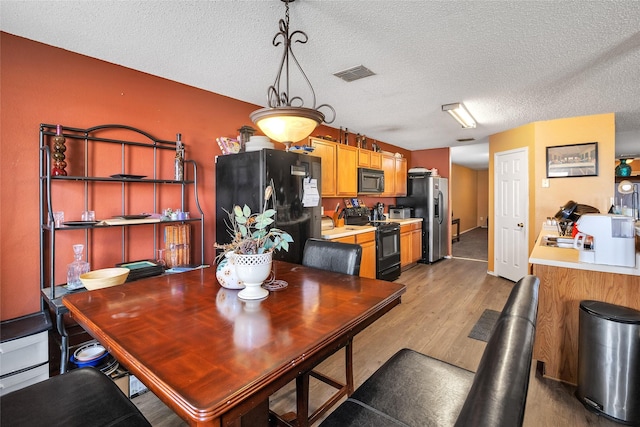 dining area featuring light hardwood / wood-style floors and a textured ceiling