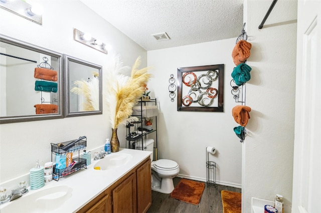 bathroom with vanity, hardwood / wood-style floors, toilet, and a textured ceiling