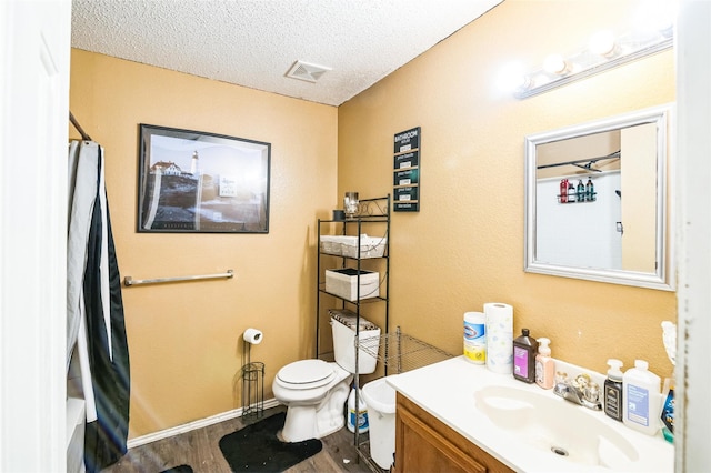 full bathroom with hardwood / wood-style floors, shower / tub combo with curtain, vanity, toilet, and a textured ceiling