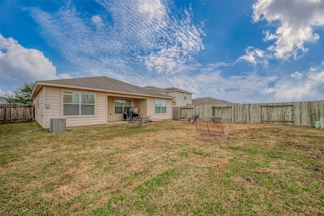 rear view of property featuring central AC and a lawn