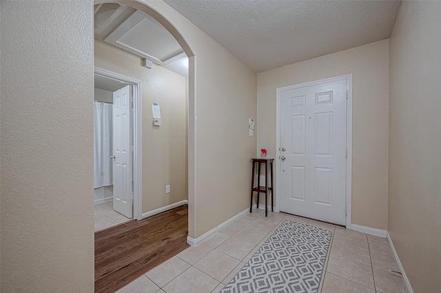 entryway with light tile patterned flooring and a textured ceiling