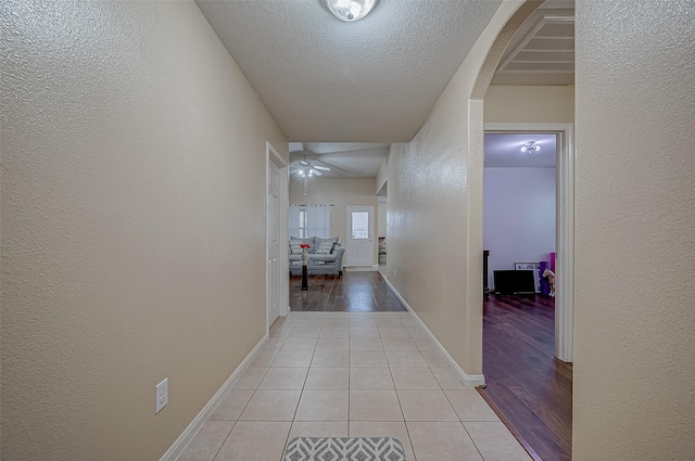 corridor with light tile patterned flooring and a textured ceiling