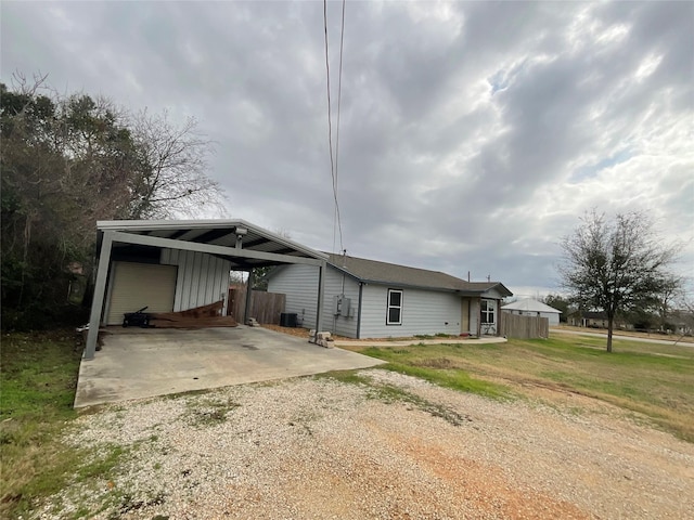 back of property with a garage, cooling unit, a carport, and a lawn