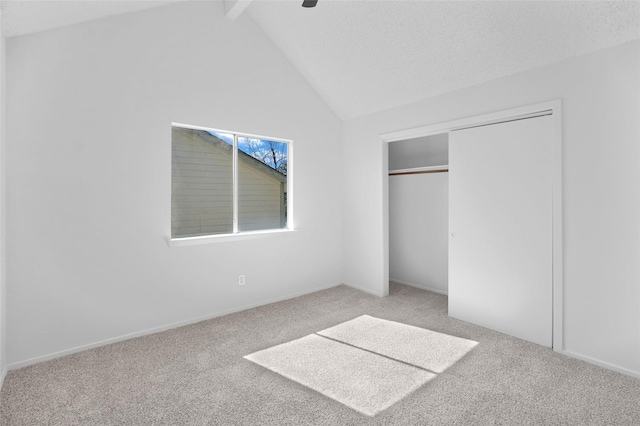 unfurnished bedroom featuring ceiling fan, carpet flooring, a closet, and vaulted ceiling with beams