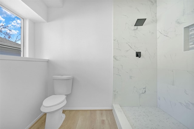 bathroom with a tile shower, hardwood / wood-style flooring, and toilet