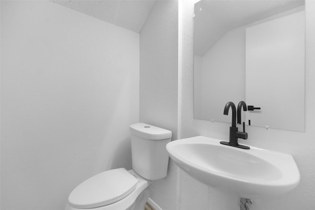 bathroom featuring sink, vaulted ceiling, and toilet