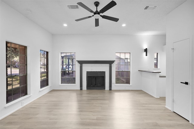 unfurnished living room featuring plenty of natural light, a tile fireplace, and light wood-type flooring