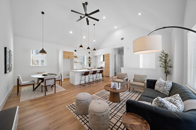 living room with ceiling fan, high vaulted ceiling, and light hardwood / wood-style flooring