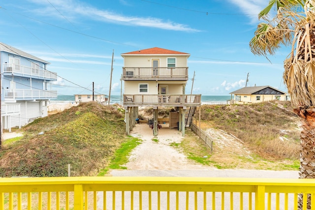 back of house featuring a carport, a balcony, and a water view