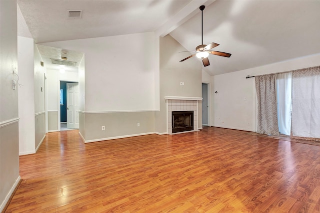 unfurnished living room with a tile fireplace, high vaulted ceiling, beamed ceiling, ceiling fan, and light wood-type flooring