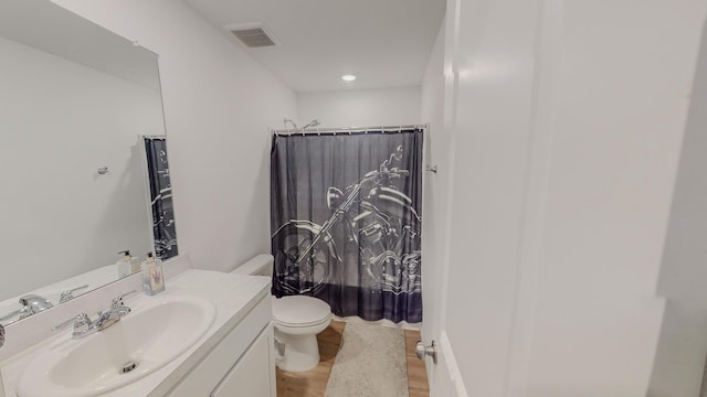 full bathroom featuring hardwood / wood-style flooring, shower / tub combo with curtain, vanity, and toilet