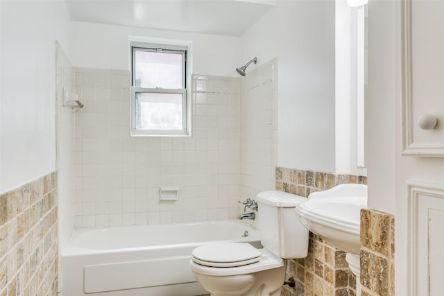 bathroom featuring tiled shower / bath, tile walls, and toilet