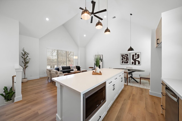 kitchen with built in microwave, white cabinetry, decorative light fixtures, and light wood-type flooring