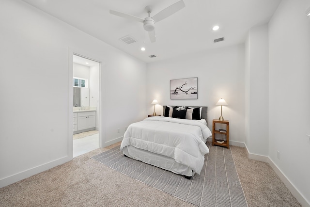 bedroom with ceiling fan, light colored carpet, and ensuite bath