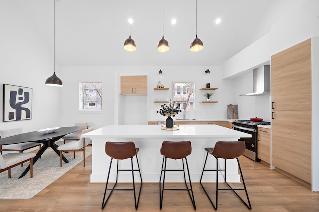 kitchen featuring wall chimney range hood, hanging light fixtures, plenty of natural light, and gas stove