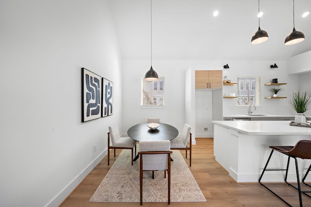 dining room with lofted ceiling, sink, and light wood-type flooring