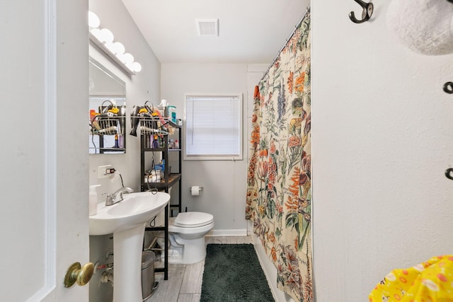 bathroom featuring walk in shower, toilet, sink, and hardwood / wood-style flooring