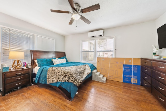 bedroom with ceiling fan, hardwood / wood-style floors, and a wall unit AC