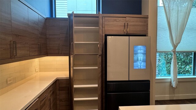 interior space with fridge, dishwashing machine, and decorative backsplash