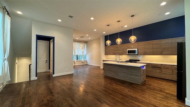 kitchen with tasteful backsplash, an island with sink, sink, dark hardwood / wood-style flooring, and hanging light fixtures