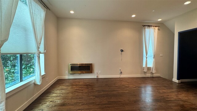 unfurnished living room featuring heating unit and dark hardwood / wood-style flooring