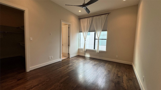 unfurnished bedroom with ceiling fan, a walk in closet, and dark hardwood / wood-style flooring