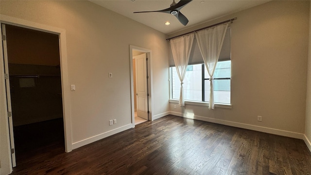 unfurnished bedroom featuring dark wood-type flooring, a walk in closet, a closet, and ceiling fan