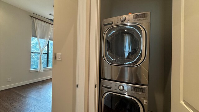 laundry area with stacked washer / dryer and dark wood-type flooring