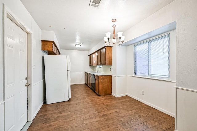 kitchen with sink, hardwood / wood-style flooring, dishwasher, a notable chandelier, and white fridge